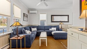Ein modernes Wohnzimmer mit einer Eckcouch, einem kleinen weißen Tisch und zwei Stehlampen.