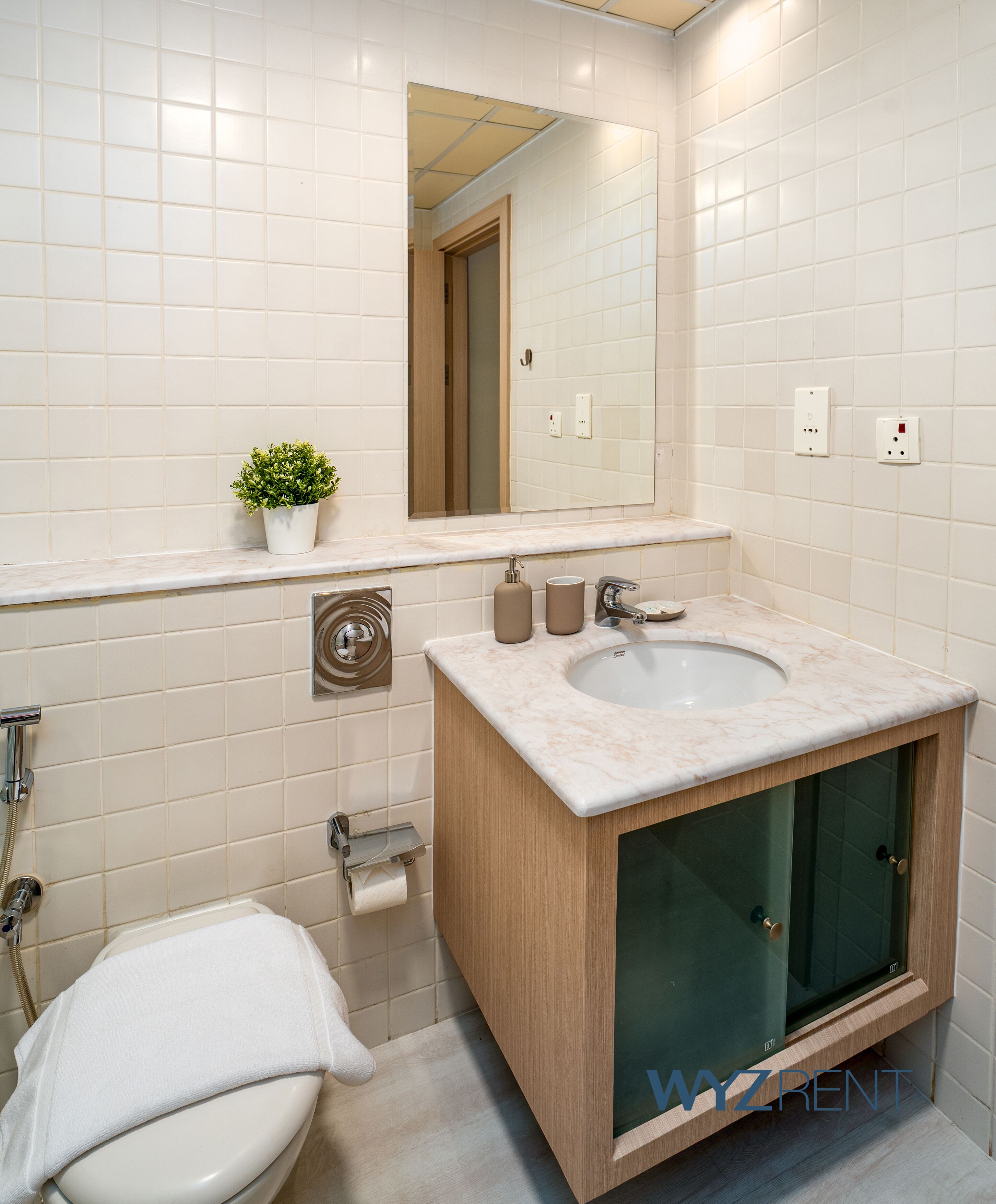 A modern bathroom with a marble sink, glass shower enclosure, and a toilet with a towel.