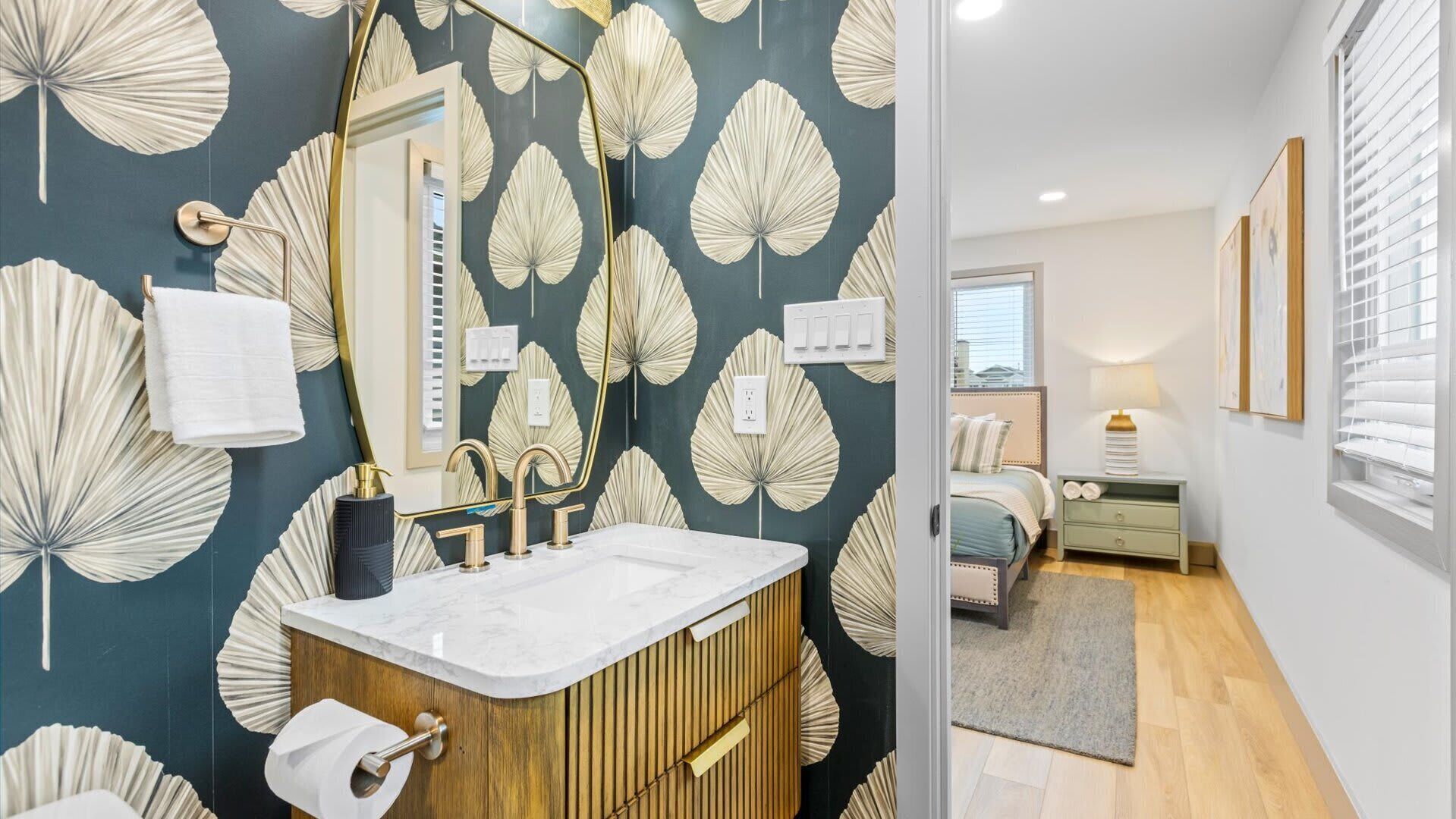 A bathroom with a vanity, mirror, and toilet paper holder.