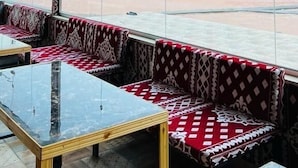 Quarto com uma grande janela, assentos com padrão vermelho e uma mesa de mármore.