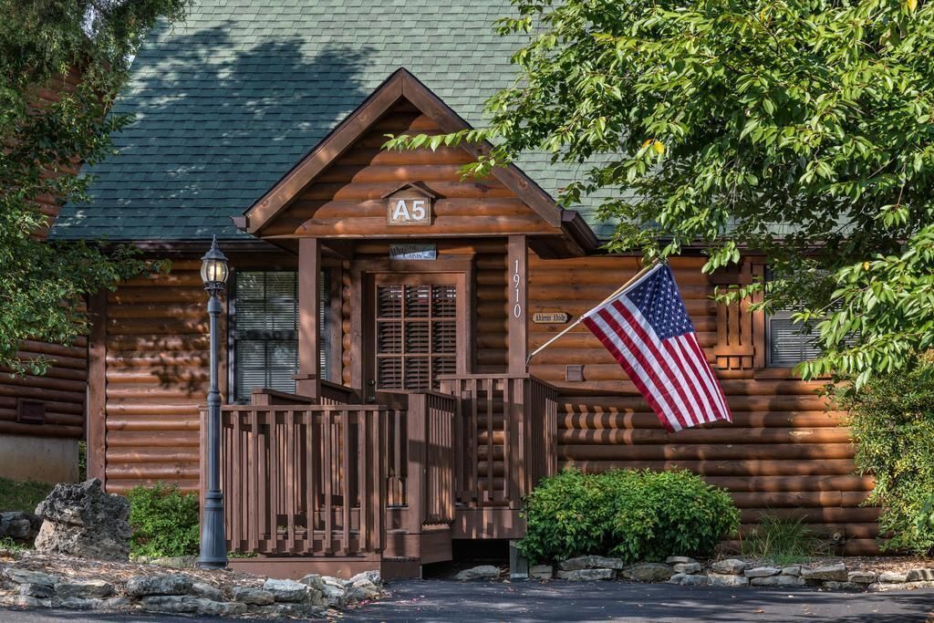 Une cabane en rondins avec un porche, un drapeau américain et une pancarte indiquant le numéro de chambre : A5.