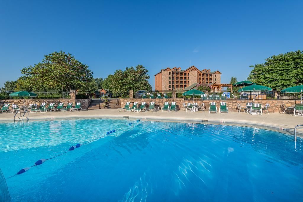 Una piscina con sillas de descanso y un edificio al fondo.