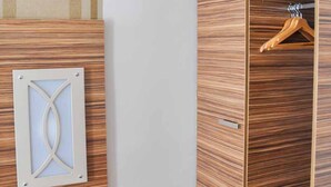 A room with a wooden wardrobe, a coat rack, and a small table with a telephone. - Erde Hotel Erlangen (Erlangen)