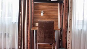 A hotel room with a bed, a desk with a chair, a television, and curtains. - Erde Hotel Erlangen (Erlangen)