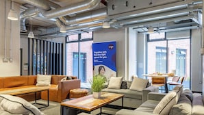 Un espacio de oficina moderno con un sofá grande, una mesa de centro y una zona de comedor.