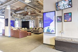 A modern interior with seating areas, a reception desk, and a mounted TV displaying a security feed. - Student Only Globe Works (Birmingham)