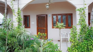 A building with a covered entrance, a wooden door, and a window with a wooden frame. - Hotel Pleasure (Ujjain)