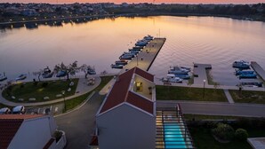 A marina with boats docked, a swimming pool, and a residential area with houses.