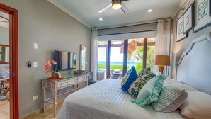 Un dormitorio con cama, escritorio, televisor y vistas al océano.