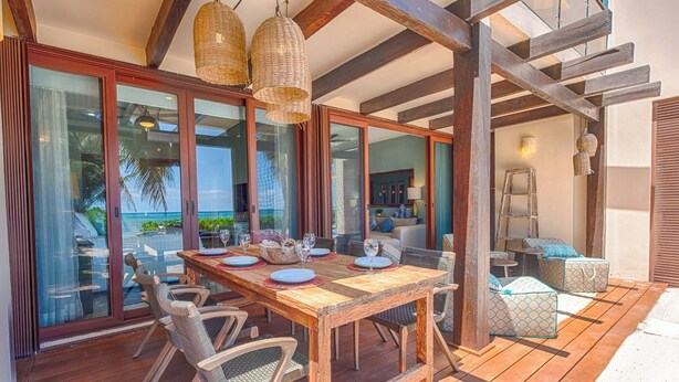 Una terraza de madera con una mesa lista para comer, con vista al océano.