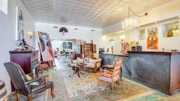 Eine großzügige Lobby mit hoher Decke, einem Chandelier, einem Empfangsschalter und verschiedenen Möbelstücken, darunter eine Couch, Sessel und ein Couchtisch.