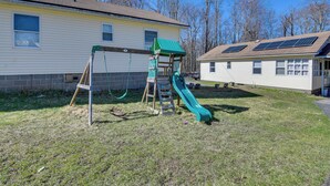 A residential area with a house featuring a green play structure and solar panels on the roof. - Shared Lake Access & Fire Pit: Catskills Getaway! (Ellenville)