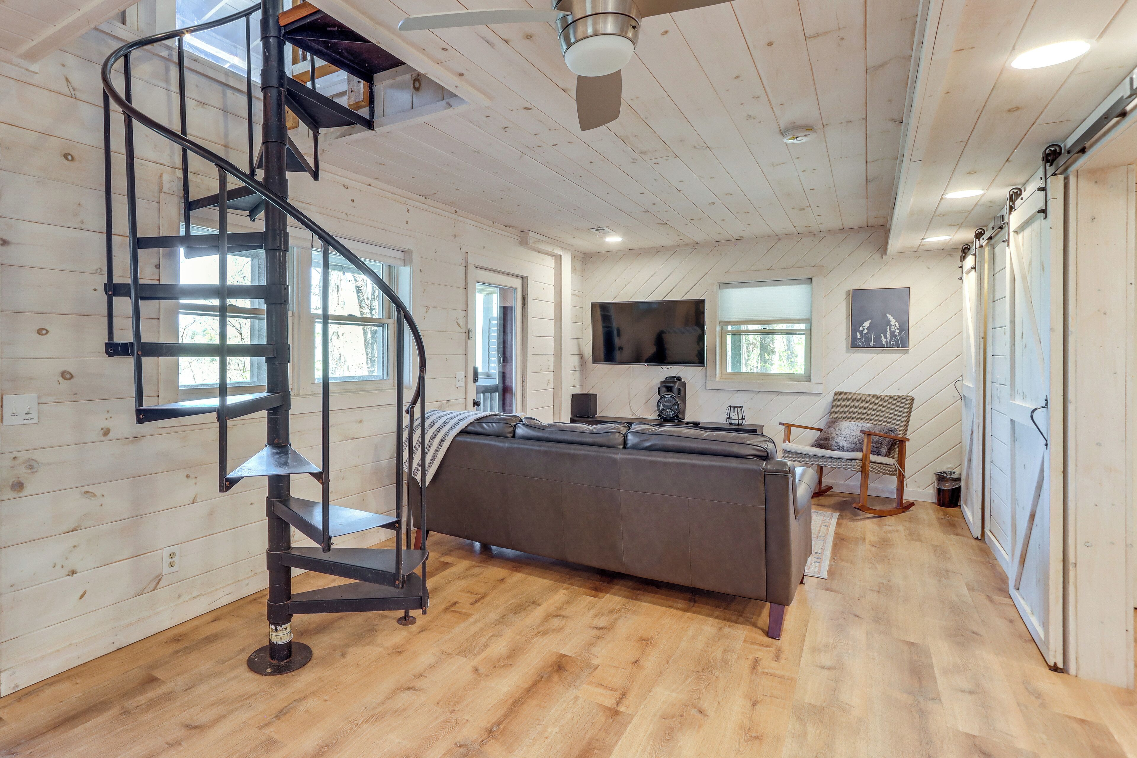 A modern interior with a spiral staircase, a sofa, a television, and a chair.