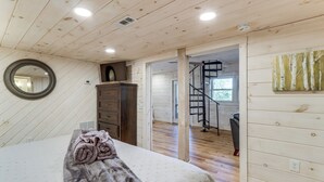 Ein Schlafzimmer mit einem Bett, einem Schminktisch, einem Spiegel und einer Wendeltreppe, die in einen anderen Raum führt.