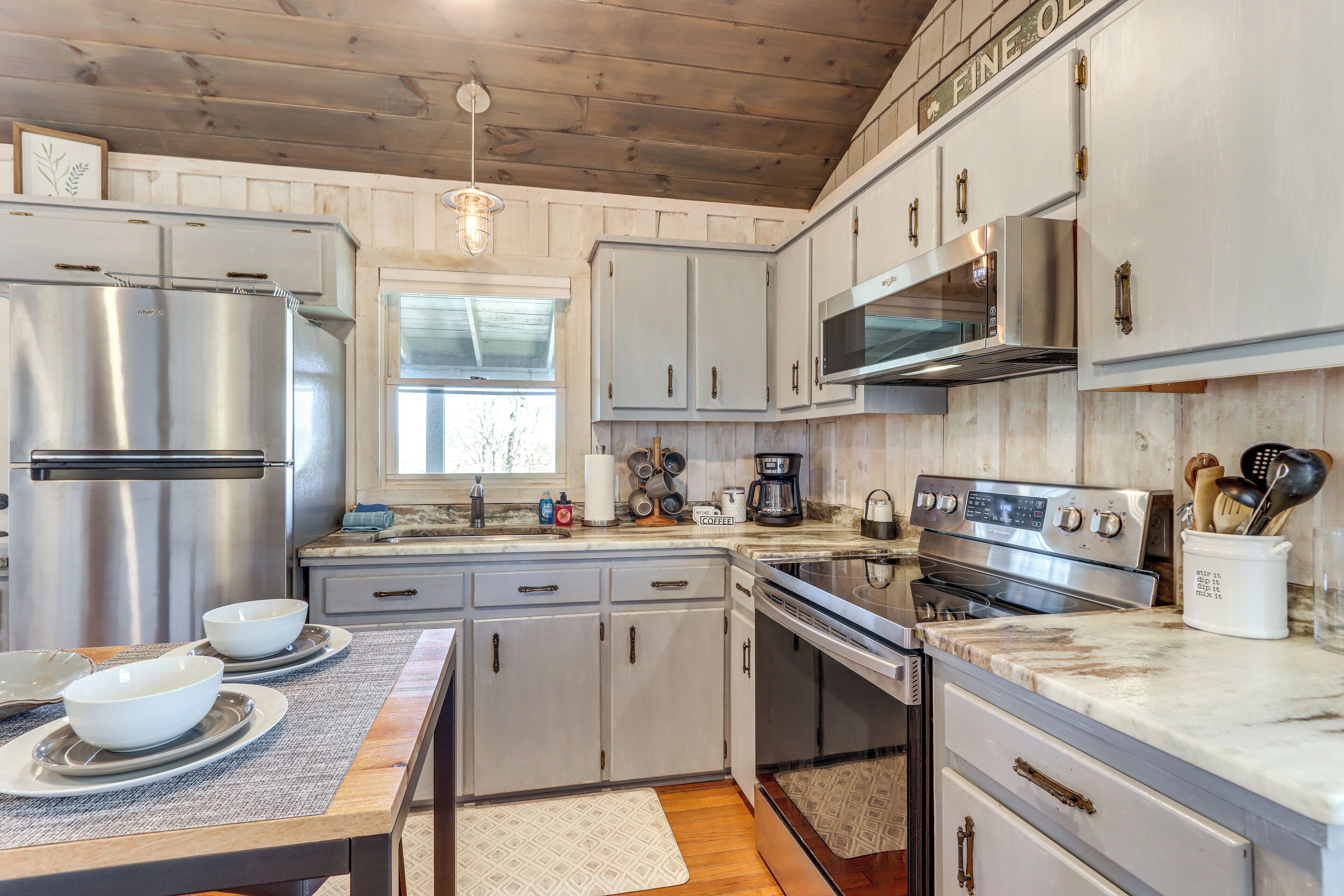 A modern kitchen with stainless steel appliances, white cabinetry, and a marble countertop.