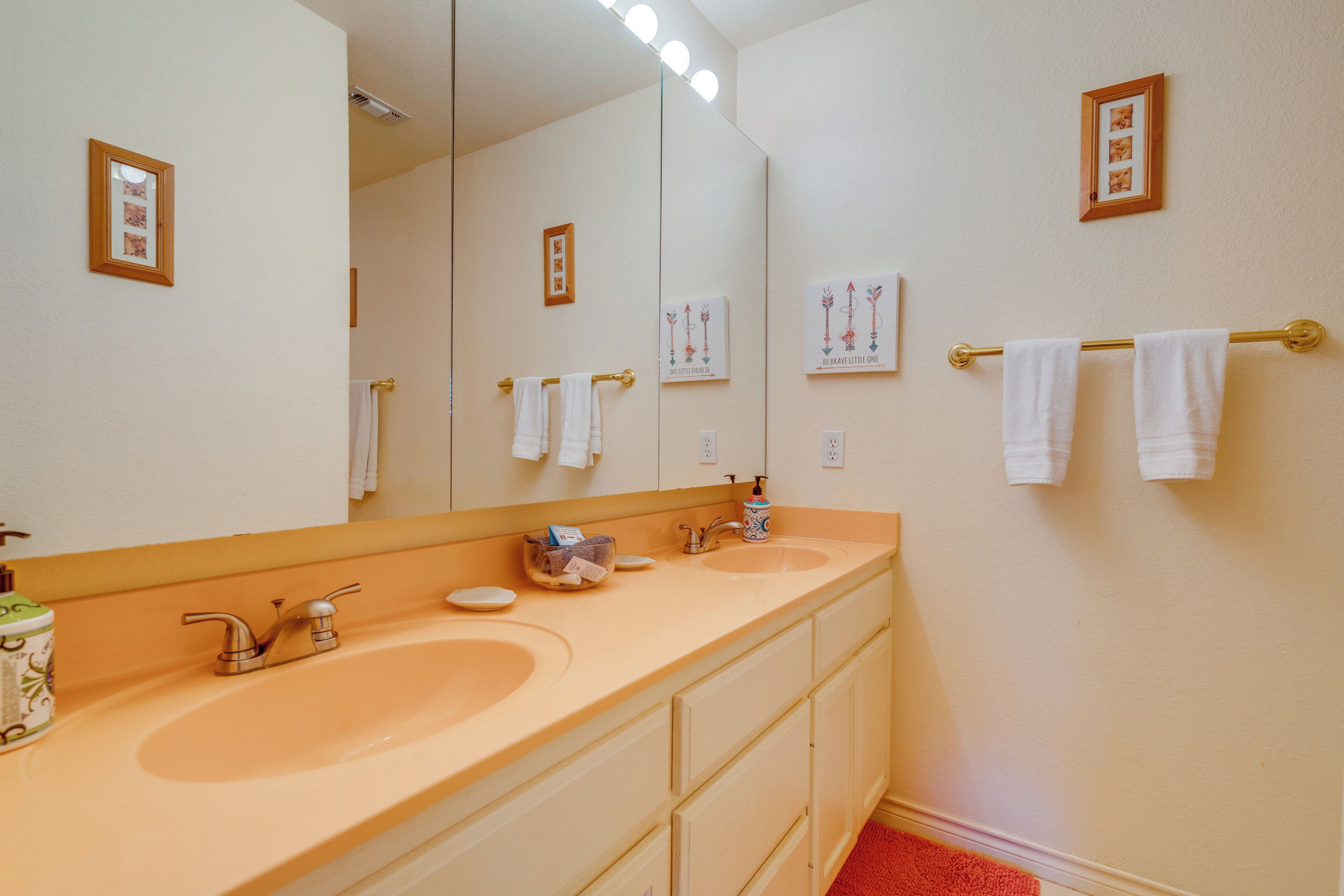 Een badkamer met twee wasbakken, een grote spiegel en een handdoekrek.
