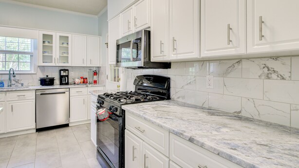 A modern kitchen with white cabinetry, a stainless steel dishwasher, a gas stove, and a microwave. - 10 Mi to Augusta: Georgia Family Home w/ Yard (Augusta)