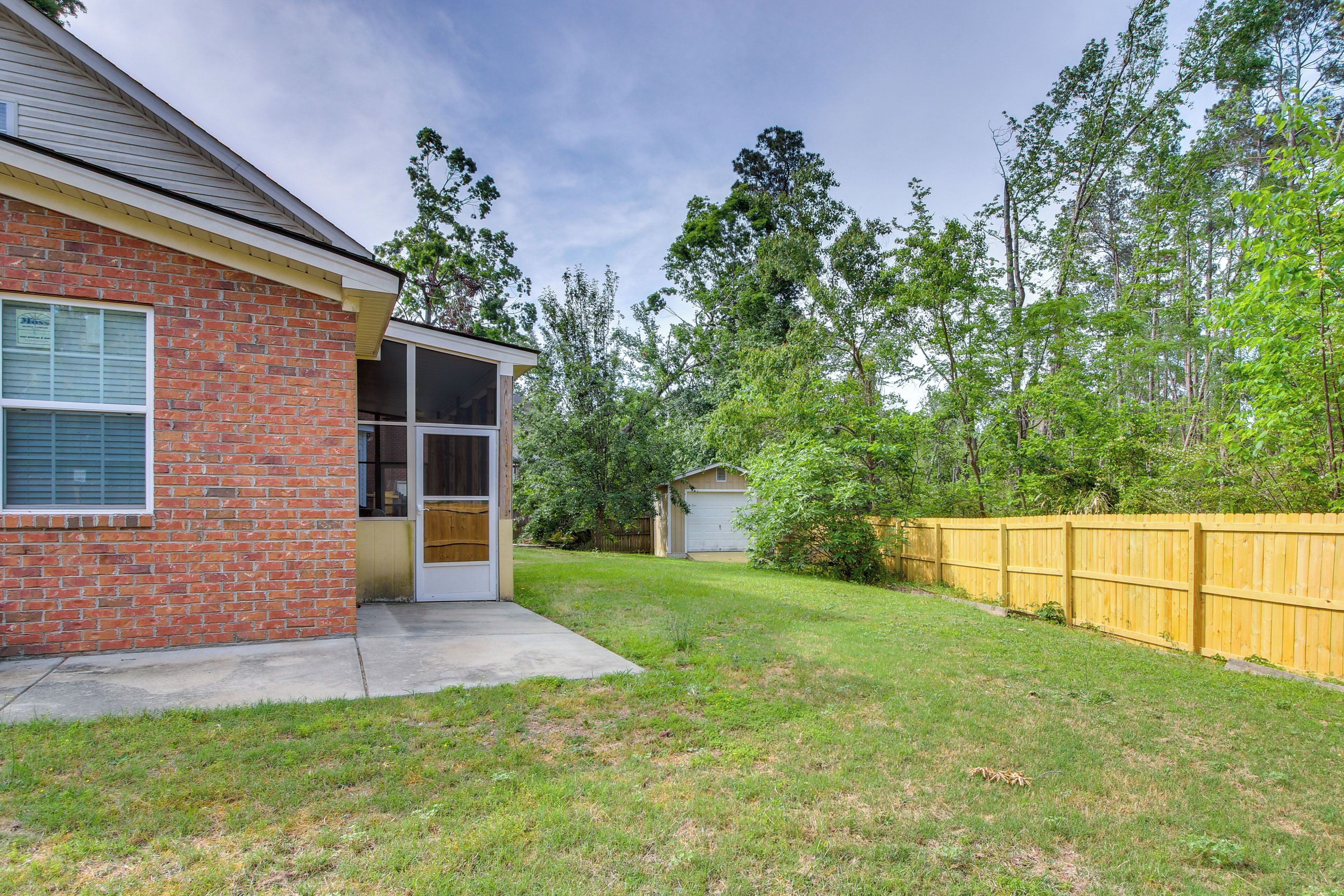 A backyard with a brick house, a wooden fence, and a garage.