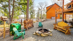 A rustic cabin with a fire pit, outdoor seating, and a stack of firewood. - Waterfront Anglers Oasis in The Maine Highlands! (Carmel)