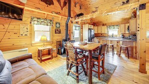 A cozy cabin interior with a wooden dining table, chairs, a sofa, and a kitchen area. - Waterfront Anglers Oasis in The Maine Highlands! (Carmel)