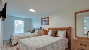 A bedroom with two beds, a wooden dresser, a nightstand, a painting, and a window with blinds. - 3 Mi to Main Street: Newly Renovated Wareham Apt! (Wareham)