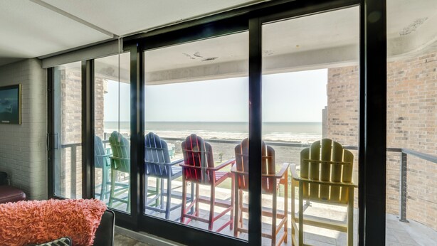 A balcony with a view of the ocean, featuring colorful Adirondack chairs and a plush chair. - 7th-floor Oceanfront Unit w/ Pools in Port Aransas (Port Aransas)