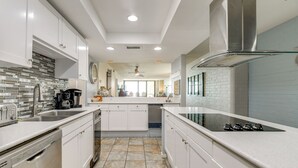 A modern kitchen with white cabinetry, a stainless steel range hood, and a tiled backsplash. - 7th-floor Oceanfront Unit w/ Pools in Port Aransas (Port Aransas)