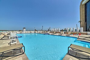 A clear blue pool with lounge chairs and a lifeguard stand. - 7th-floor Oceanfront Unit w/ Pools in Port Aransas (Port Aransas)