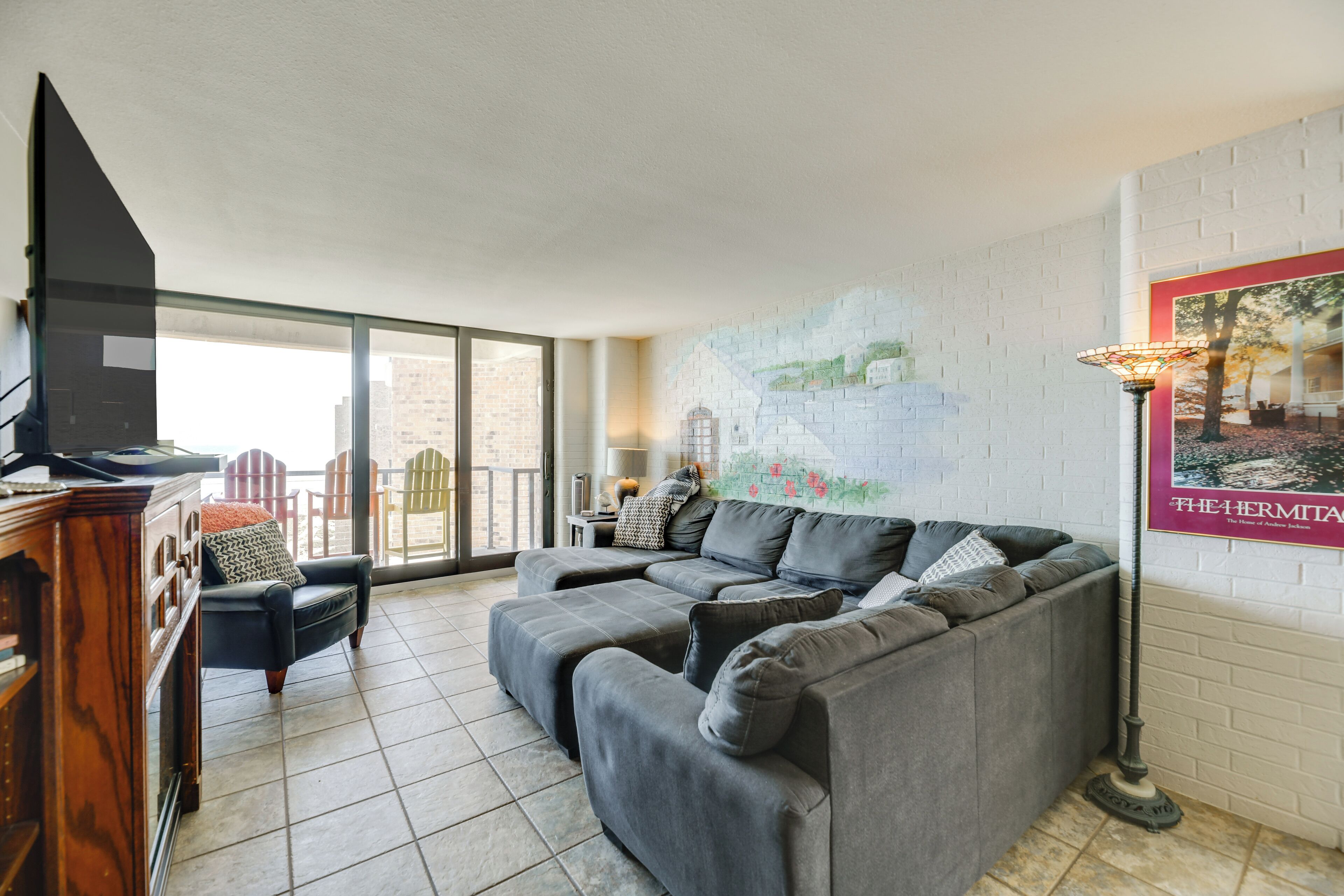 Una sala moderna con un sofá modular gris, un mueble de madera y un televisor de pantalla plana.