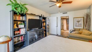 A bedroom with a large bed, a bookshelf, a television, and a ceiling fan. - 7th-floor Oceanfront Unit w/ Pools in Port Aransas (Port Aransas)