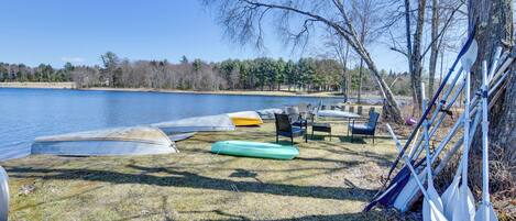 Um camping à beira do lago, com canoas, prancha de remo e uma tenda.