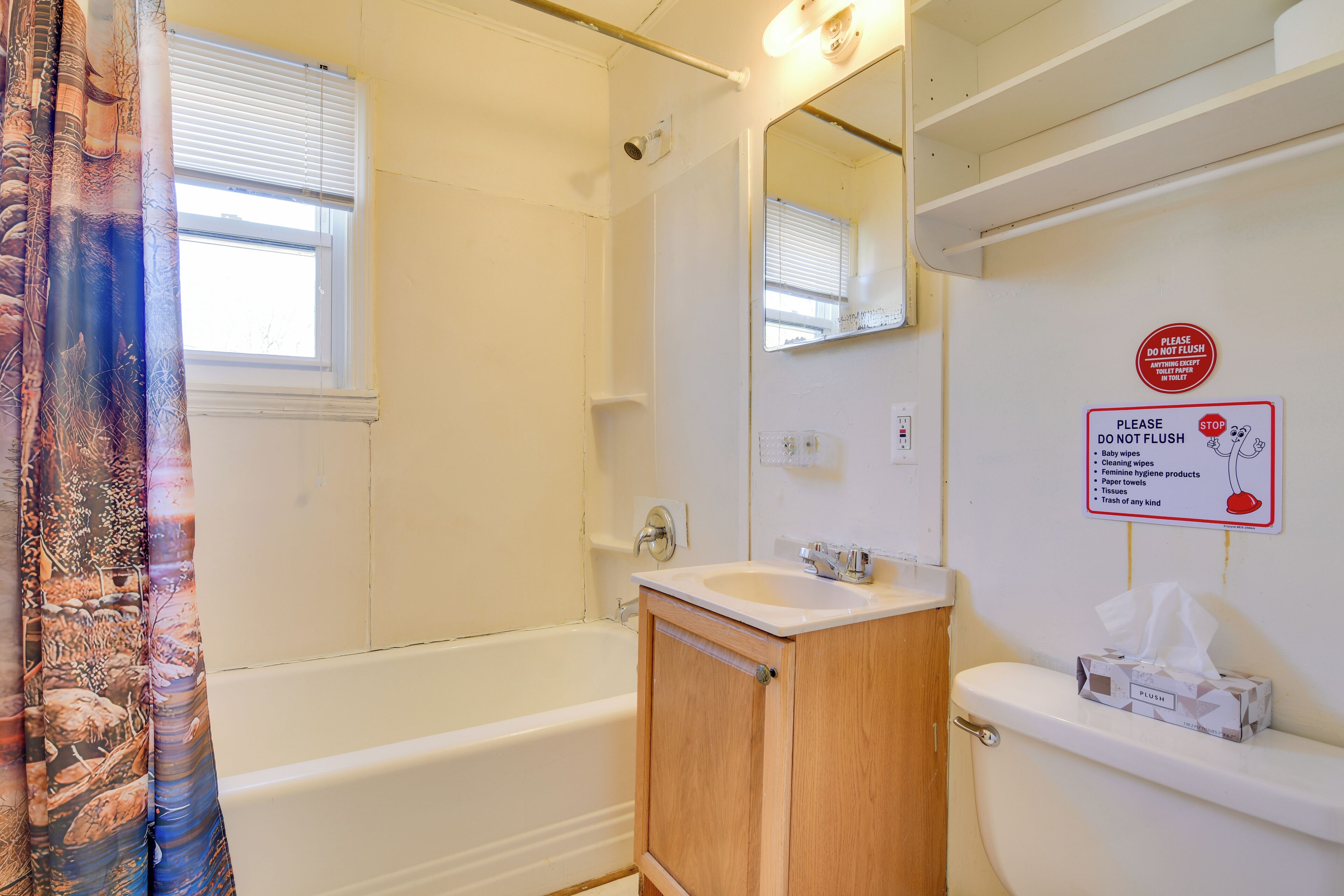 A bathroom with a bathtub, a sink, and a toilet. There is a sign on the wall with a list of items not to flush.