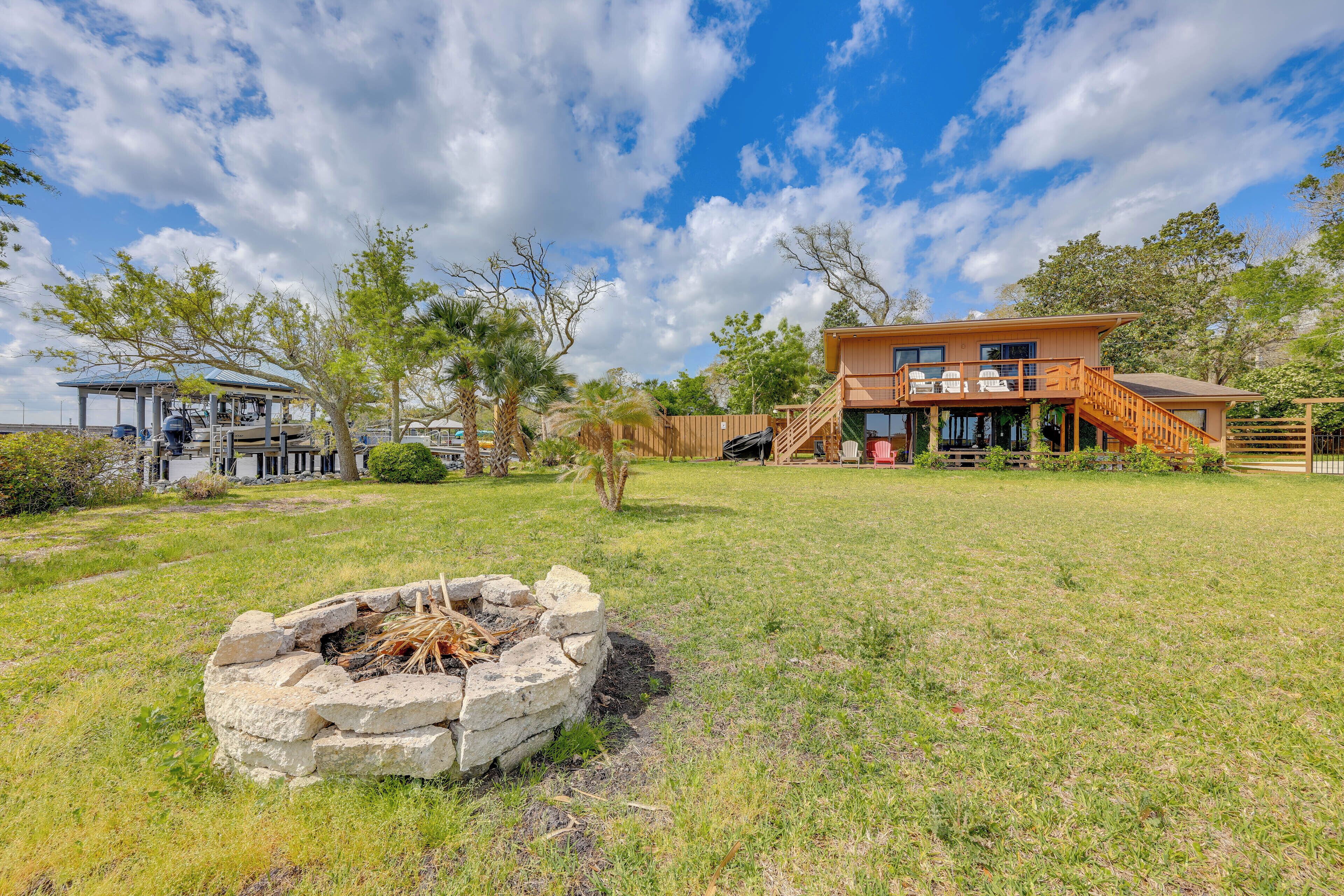 A two-story house with a deck, a fire pit, and a covered outdoor seating area.