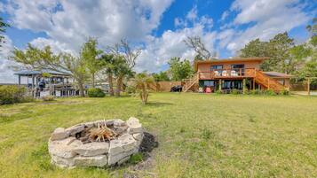 A two-story house with a deck, a fire pit, and a covered outdoor seating area.