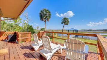 Relax on the deck with a clear view of the lake, surrounded by Adirondack chairs and a grill area.