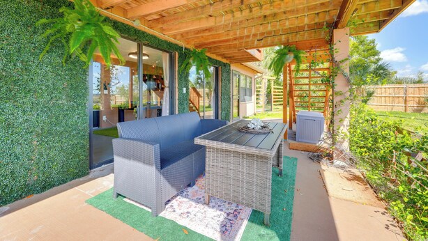 Une terrasse couverte avec un canapé bleu, une table en osier et un plafond orné de poutres en bois.