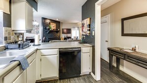 Une cuisine moderne avec des meubles blancs, un lave-vaisselle et un plan de travail en bois foncé.