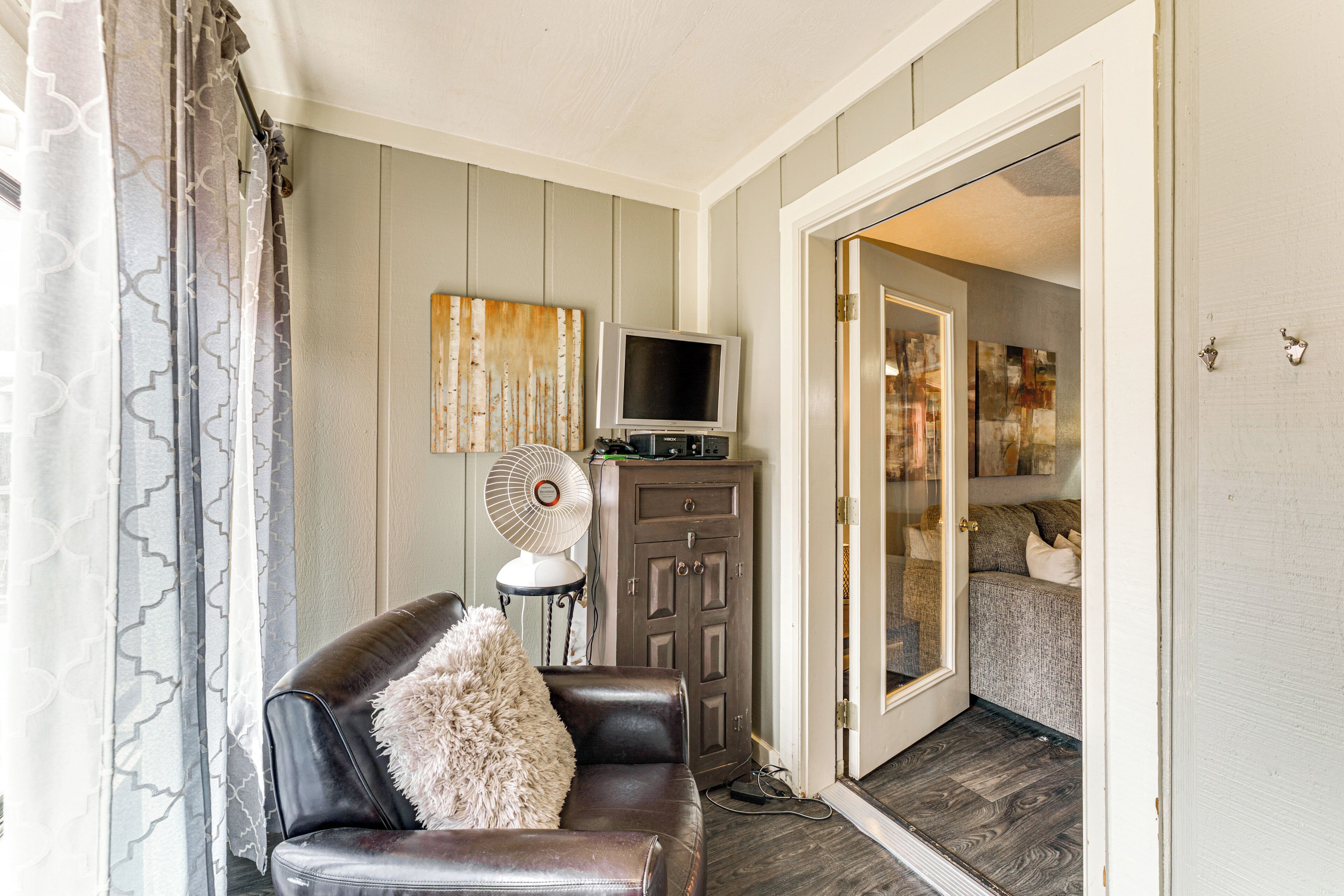 A living room with a leather sofa, a television, a cabinet, and a door leading to another room.
