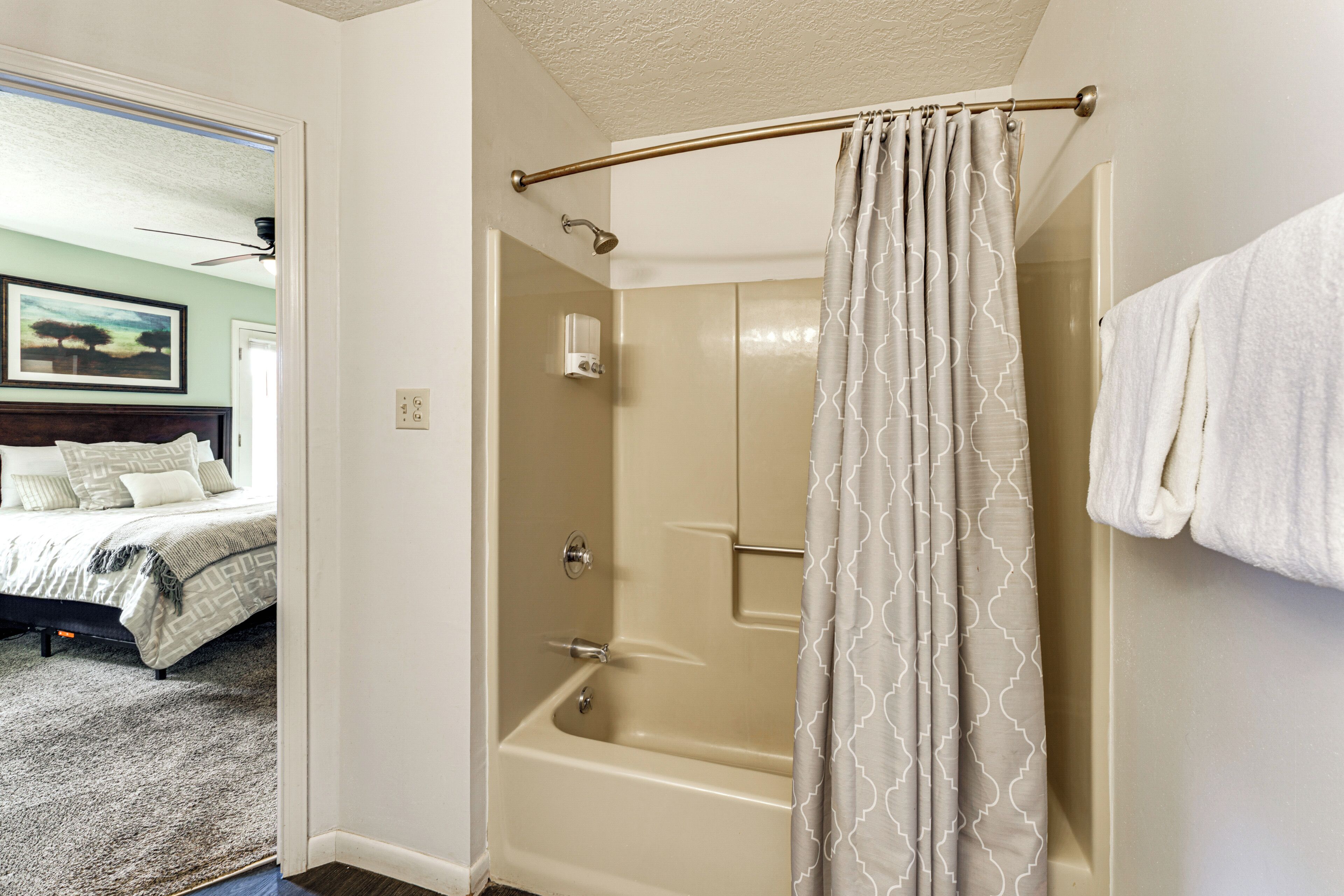 A bathroom with a bathtub, shower curtain, and a towel rack.