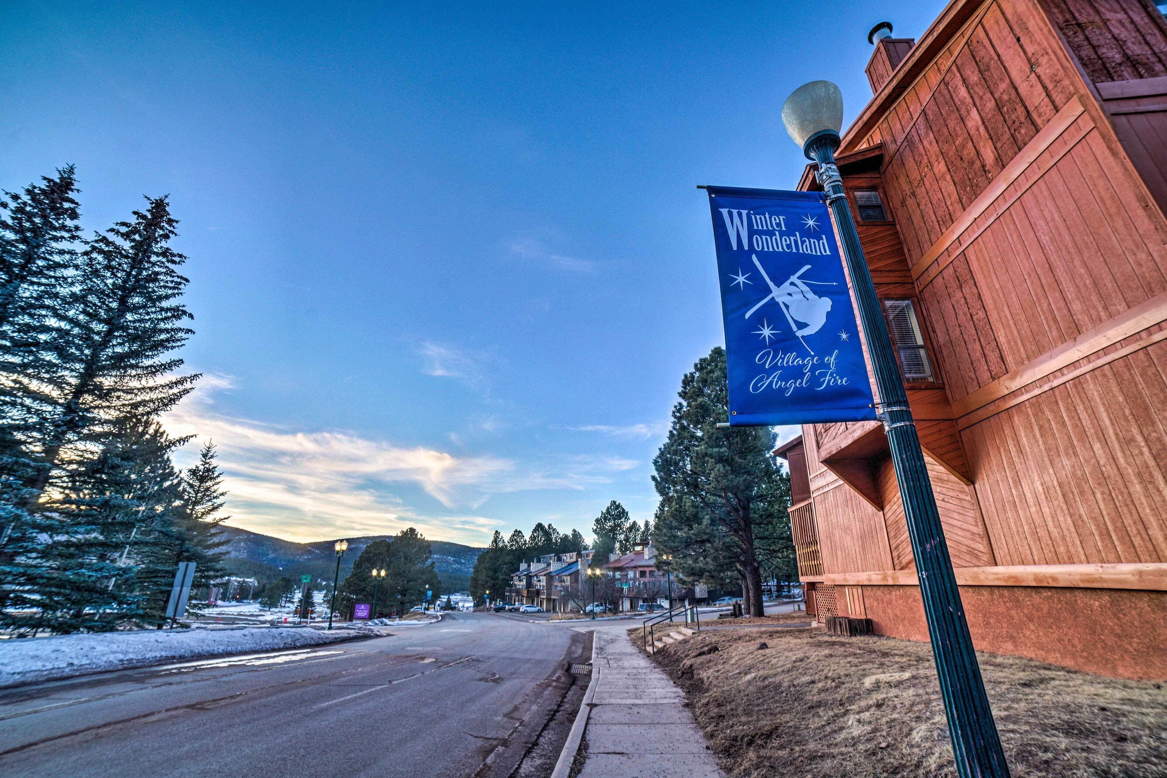 A street view with a wooden building and a sign for Winter Wonderland Village of Angel Fire.