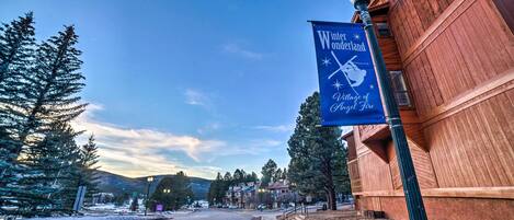 A street view with a wooden building and a sign for Winter Wonderland Village of Angel Fire.