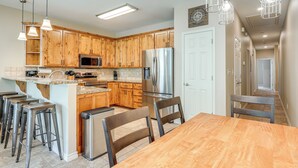 Una cocina moderna con armarios de madera, electrodomésticos de acero inoxidable y una isla central con taburetes de bar.