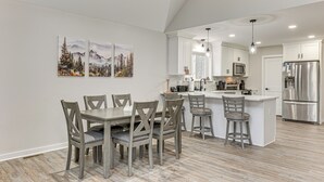A modern kitchen with white cabinetry, a stainless steel refrigerator, and a central island with bar stools.