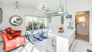 A modern kitchen with white cabinets, a marble countertop, and a dining area with a white table and chairs.