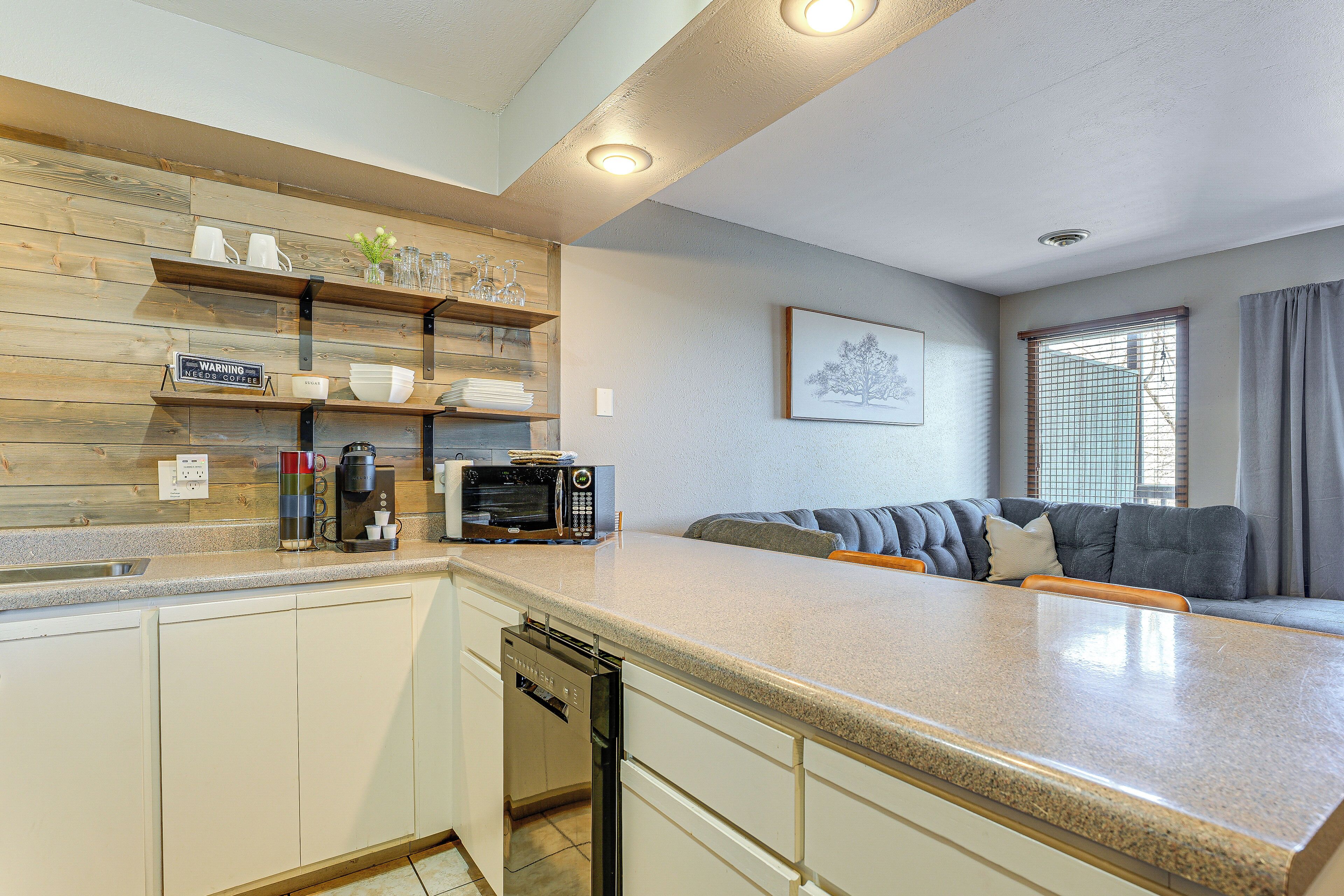 Cocina compacta con lavavajillas, microondas y cafetera en la encimera.