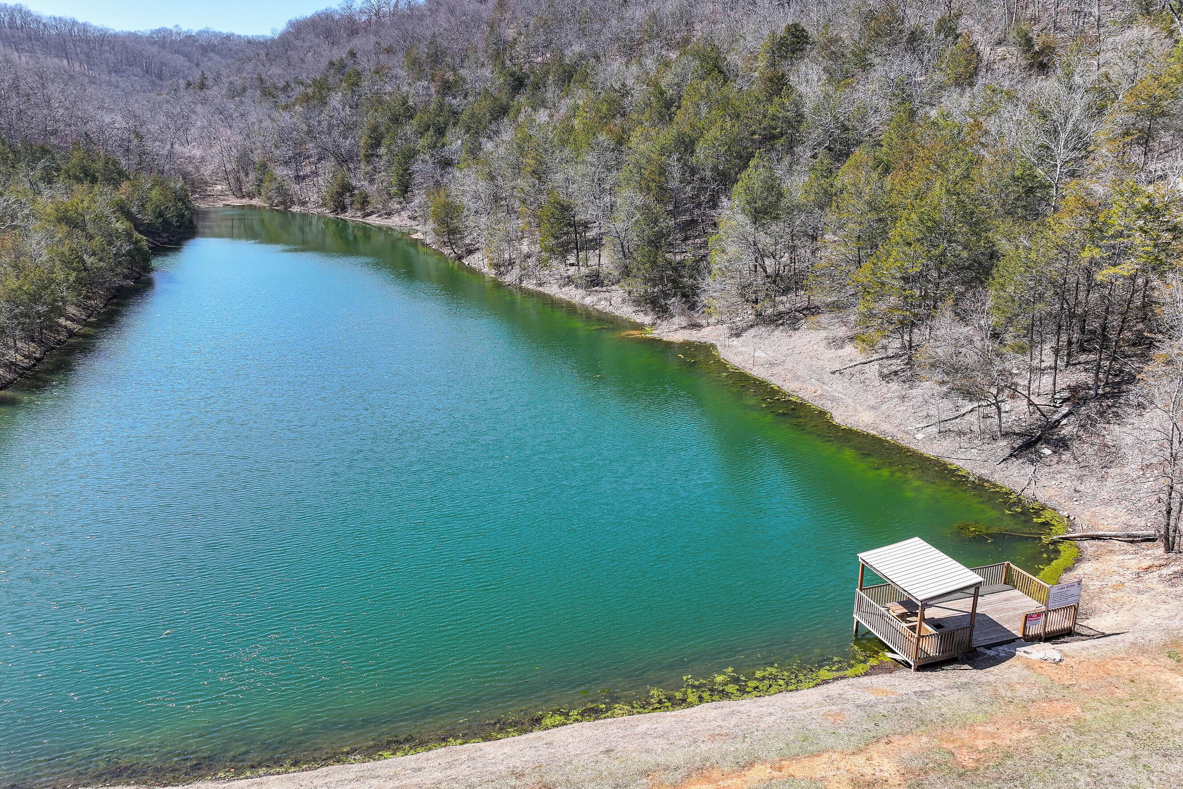 A clear view of a river with a wooden dock and a small pavilion on the right bank.
