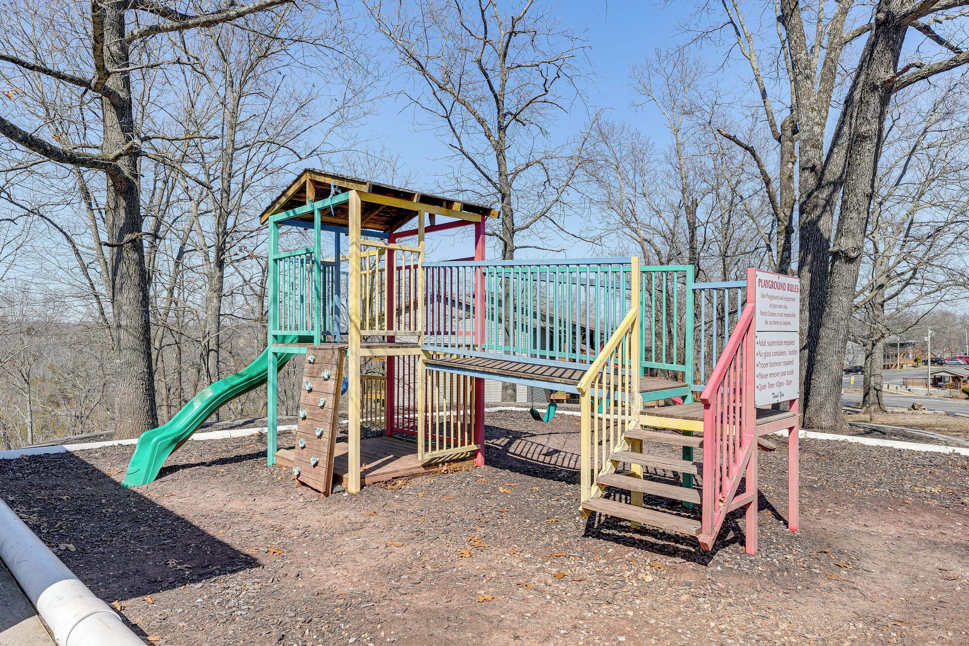 Une aire de jeux avec un toboggan, une zone d’escalade et une cabane couverte.