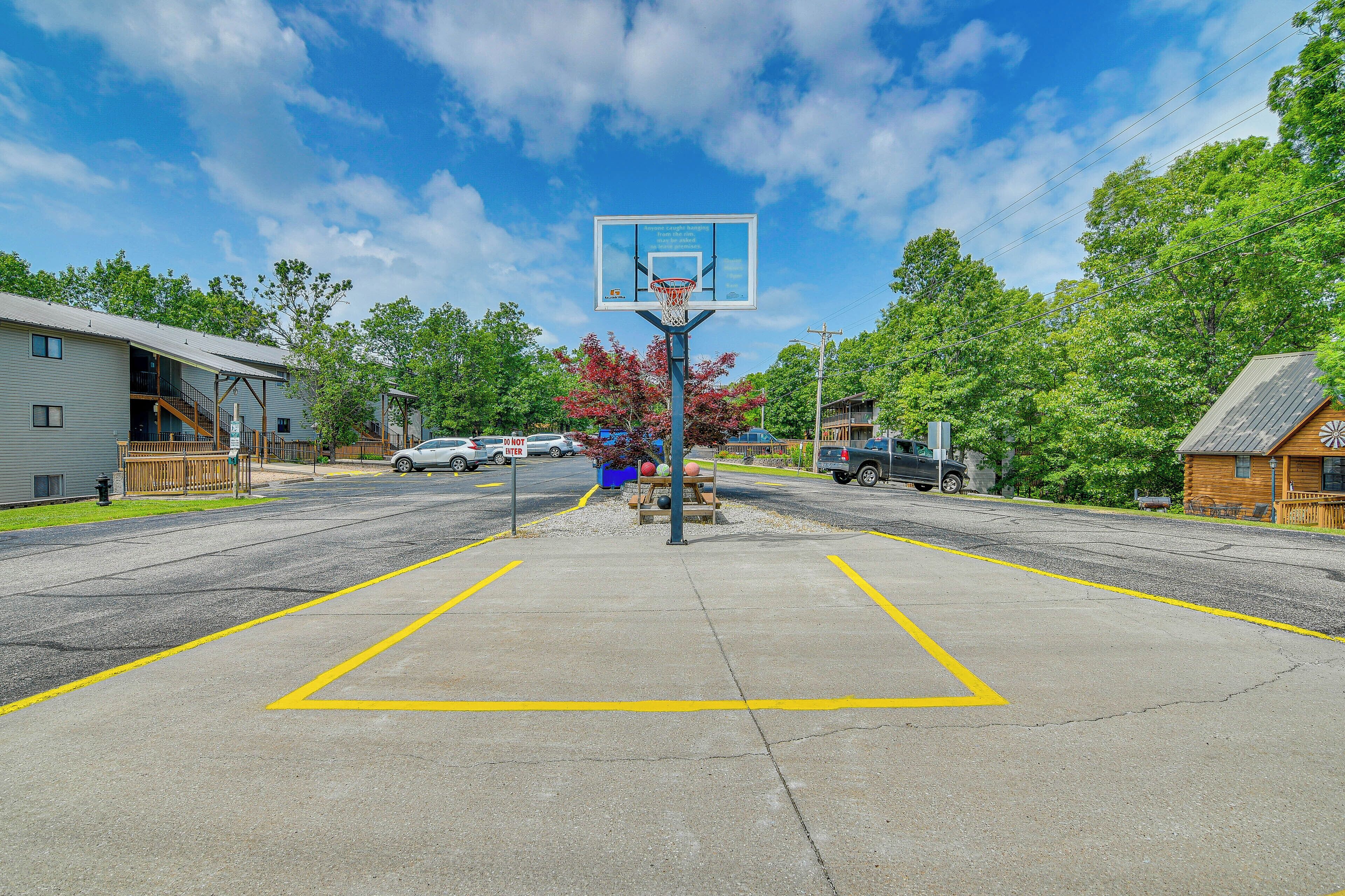 Een basketbalveld met een ring, omringd door een parkeerplaats en woongebouwen.