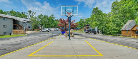 Een basketbalveld met een ring, omringd door een parkeerplaats en woongebouwen.