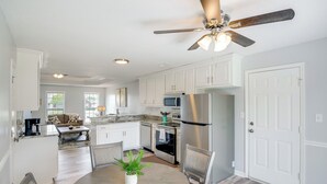 Une cuisine moderne avec des armoires blanches, des appareils en acier inoxydable et un coin repas comprenant une table ronde et des chaises.